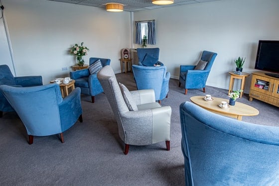 Springwater Lodge Care Home - Comfortable blue chairs in tv room