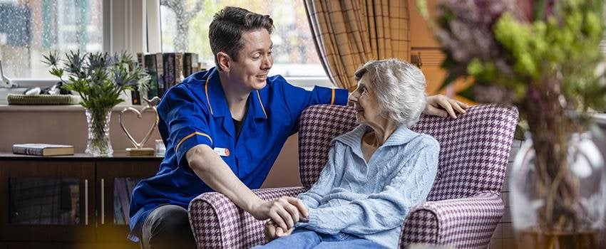 Cozy care home room with resident and staff