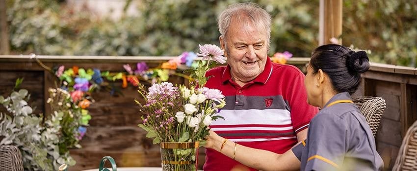 Care home resident outdoors arranging flowers
