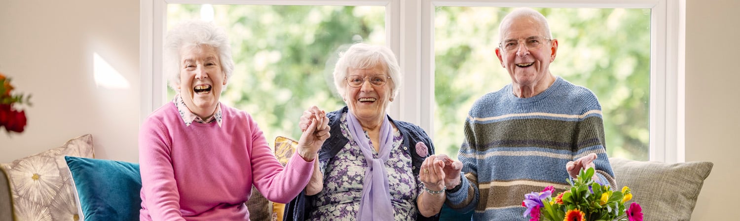 HC One care home - three happy care home residents stood by the window