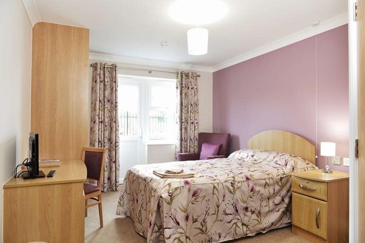 Ebor Court Care Home - Care home bedroom with single bed, wooden furniture, and purple decor